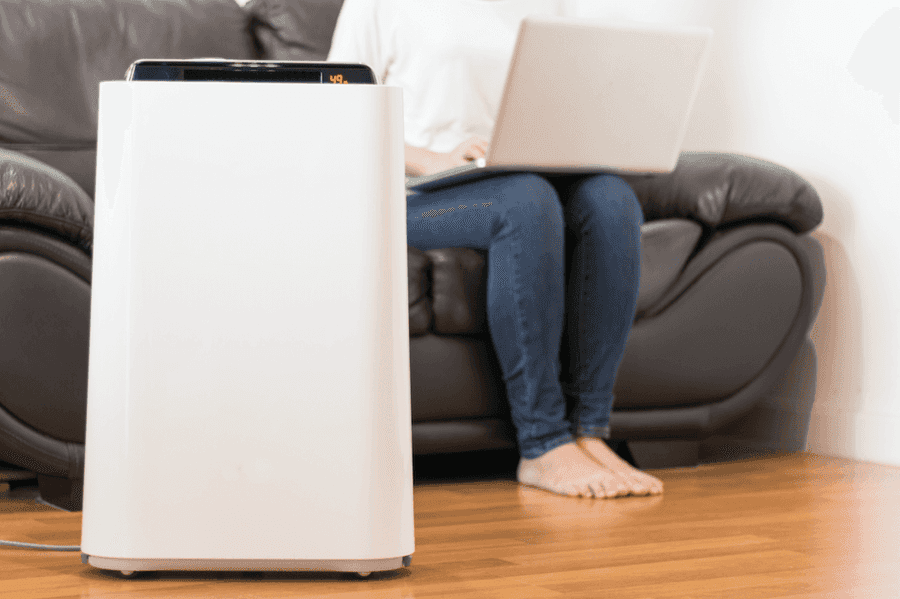 Air filter next to the legs of a person working on a laptop