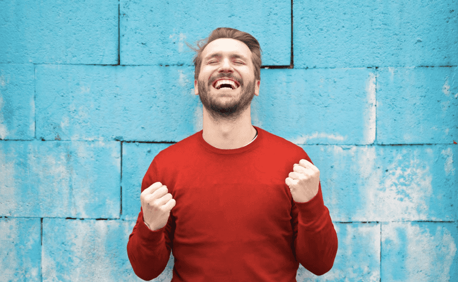 Happy man in front of a blue wall. 