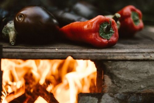 Peppers and eggplant on a grill over open flame.