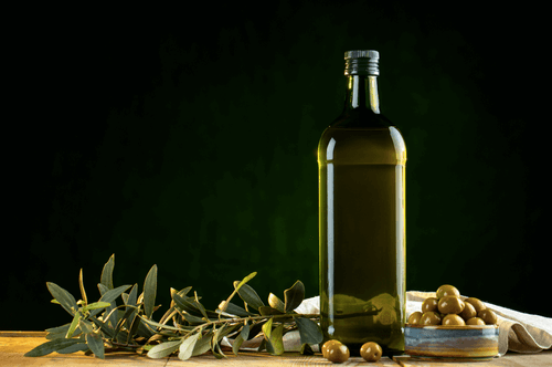 Bottle of olive oil on a table with olives.