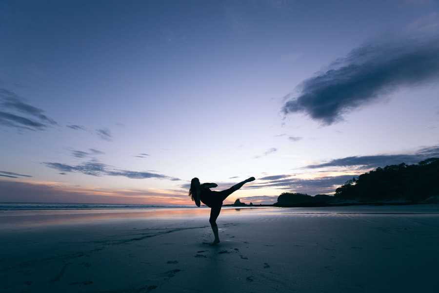 Woman on a beach kicking the air. 