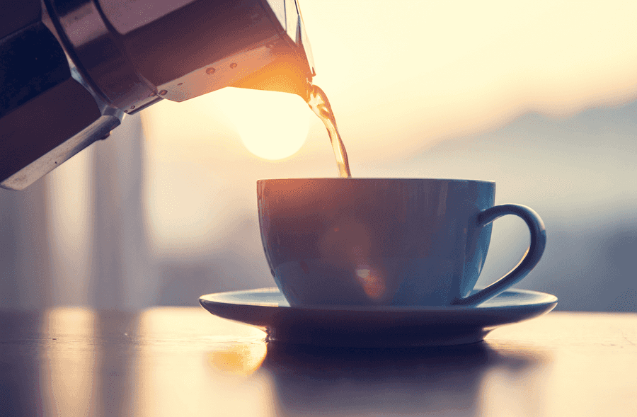 Cup of coffee in front of a sunrise