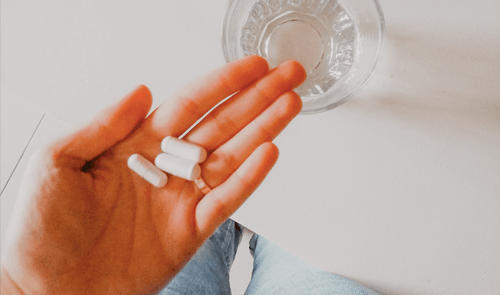 Open palm holding three capsules