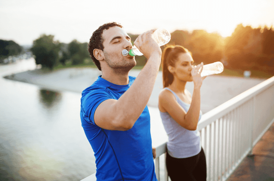 Man and woman drinking from water bottles
