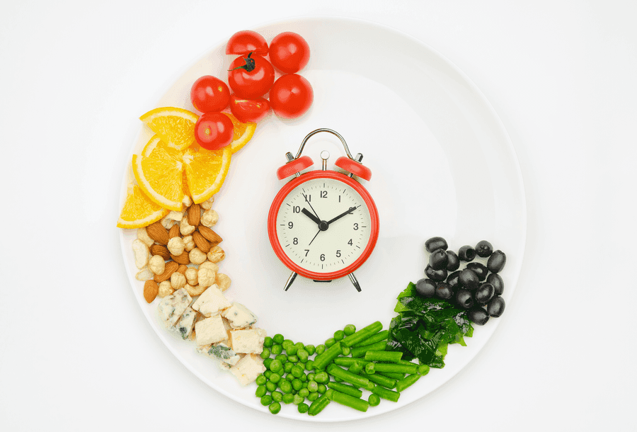 Clock on a plate surrounded by foods