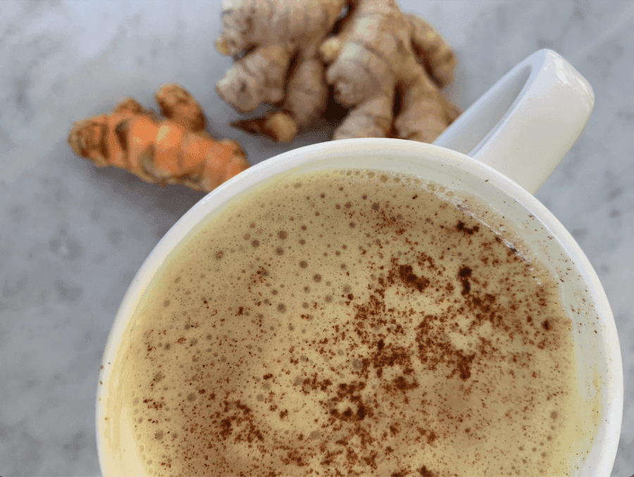 Mug full of orange, white froth and topped with cinnamon. 