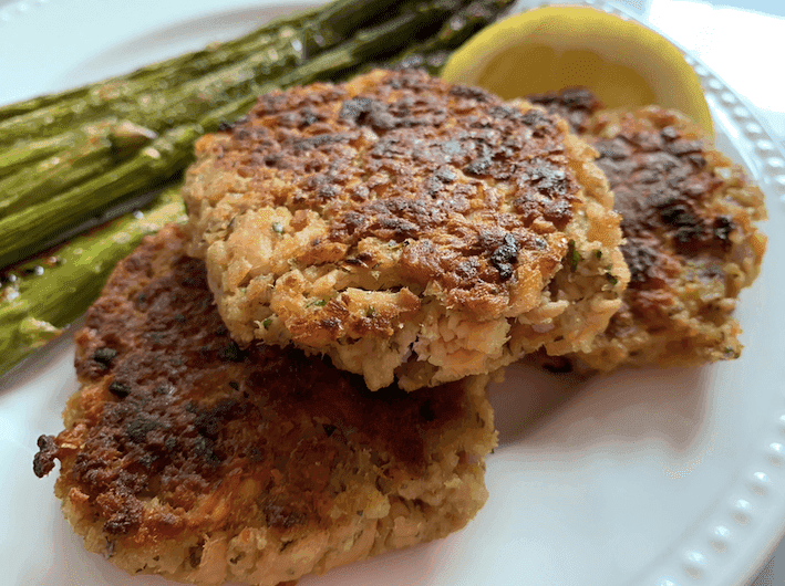 Salmon cakes and asparagus on a white plate